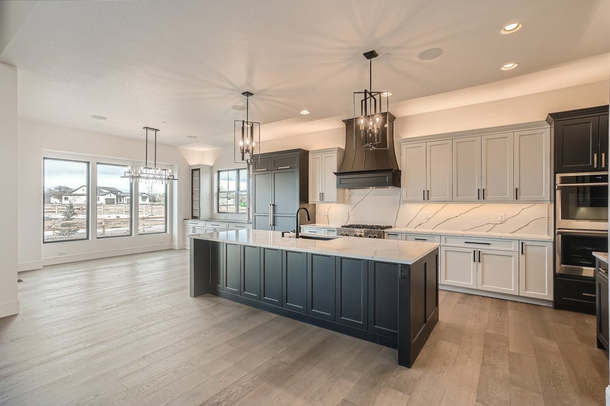 Open kitchen with a central island, elegant light fixtures, and wooden cabinetry in a Sheffield Homes home in Westminster, CO