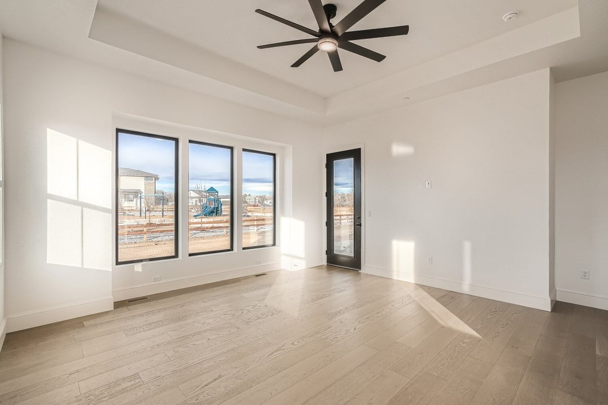 Primary bedroom with vinyl flooring, a ceiling fan, and sliding windows in a custom home by Sheffield Homes, Westminster, CO