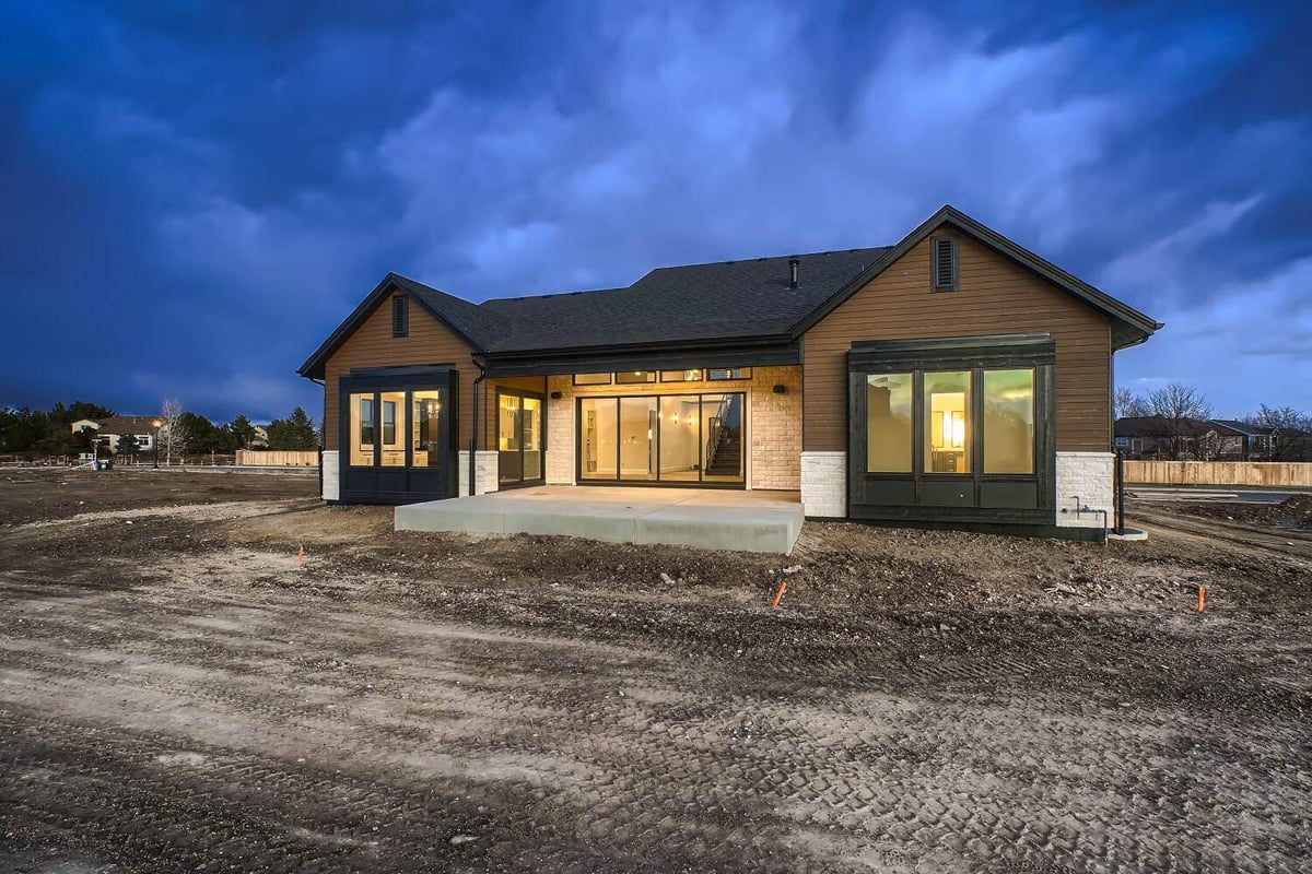 Rear exterior view of a custom home with a backyard enclosed by a boundary fence, by Sheffield Homes in Westminster, CO