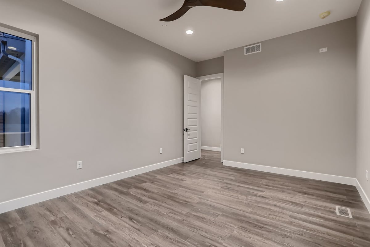 Bedroom with vinyl flooring, a ceiling fan, and a sliding window in a custom home by Sheffield Homes in Westminster, CO