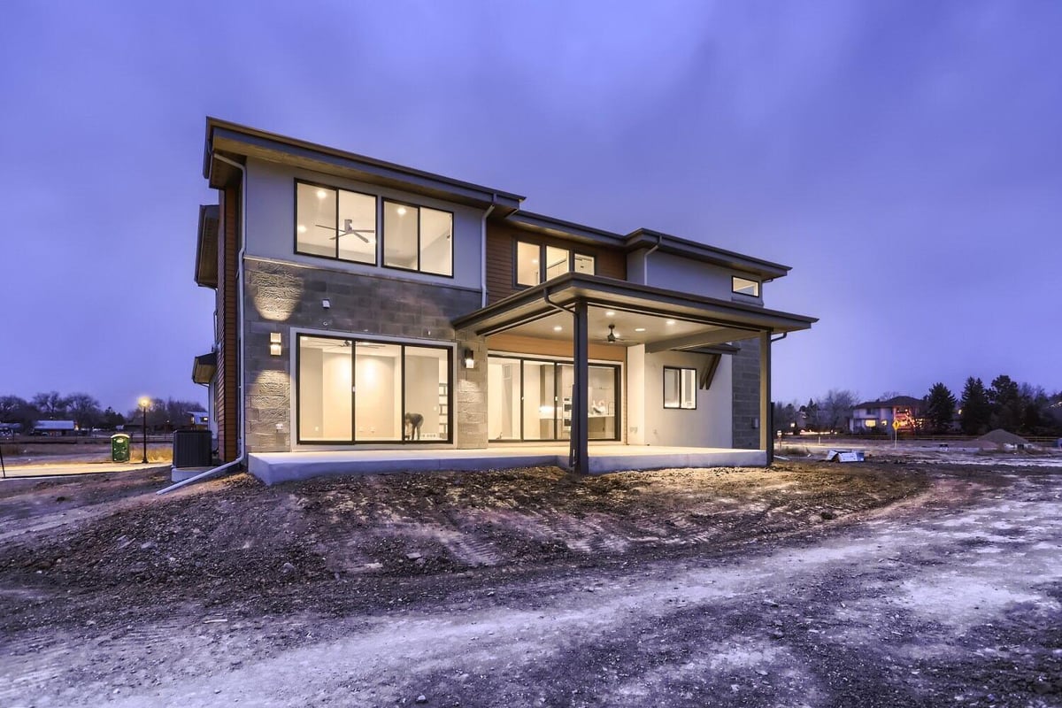 Exterior rear of a custom home with elegant bright lighting and a backyard, built by Sheffield Homes in Westminster, CO