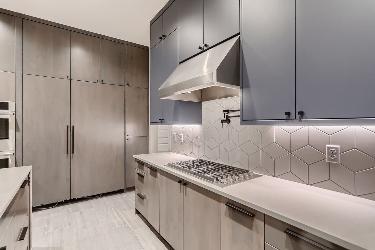 Kitchen counter with stove fixtures and extractor hood, surrounded by wooden cabinets, by Sheffield Homes in Westminster, CO