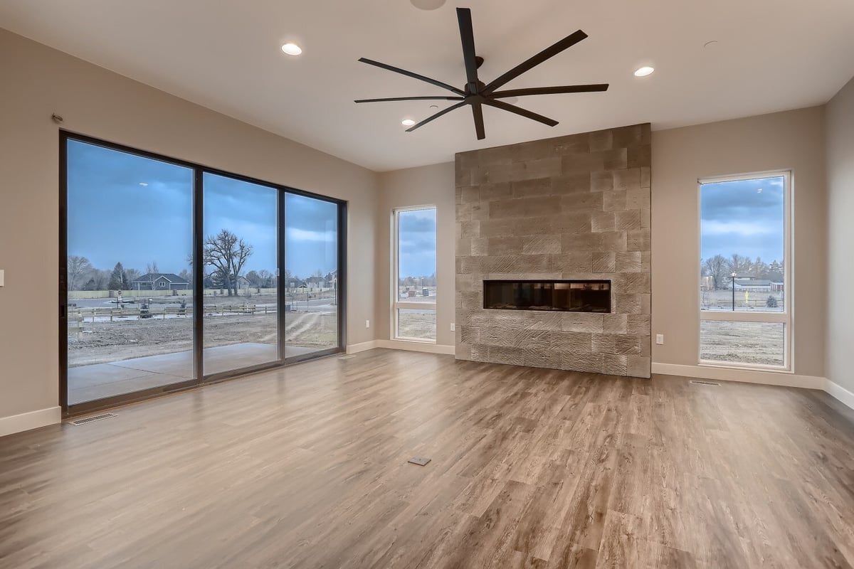 Living room with vinyl flooring, sliding doors, and a wall-mounted fireplace in a Sheffield Homes home in Westminster, CO