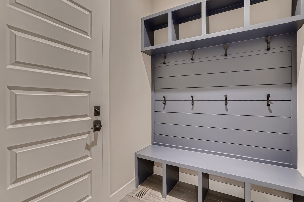 Mudroom with a seating bench, clothing hooks, and multiple storage slots for footwear, by Sheffield Homes in Westminster, CO