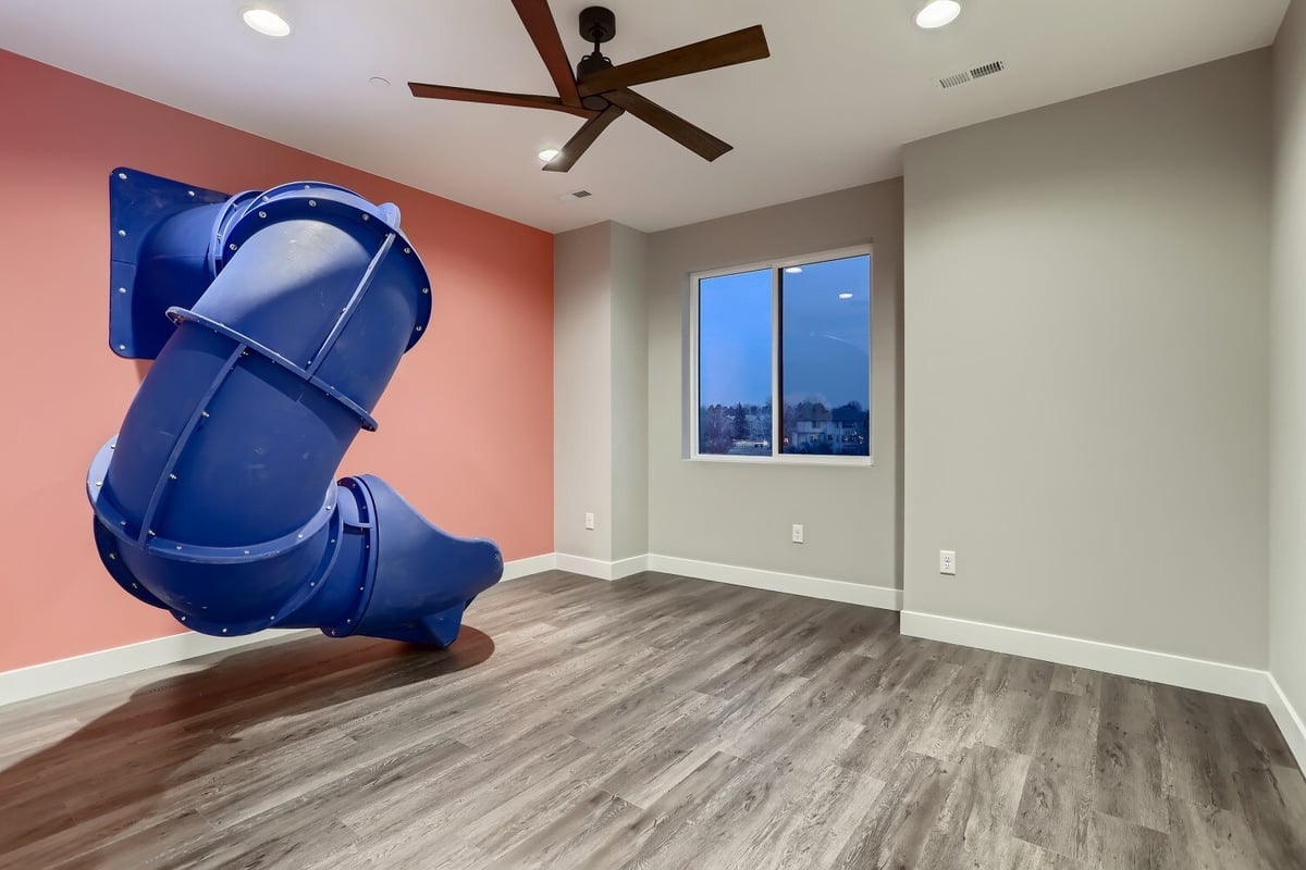 Second-floor bedroom with vinyl flooring and a rounded home slide for kids in a Sheffield Homes home in Westminster, CO