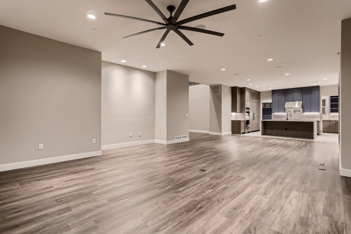 Spacious living room with vinyl flooring, a ceiling fan, and a corner open kitchen in a Sheffield Homes home, Westminster, CO