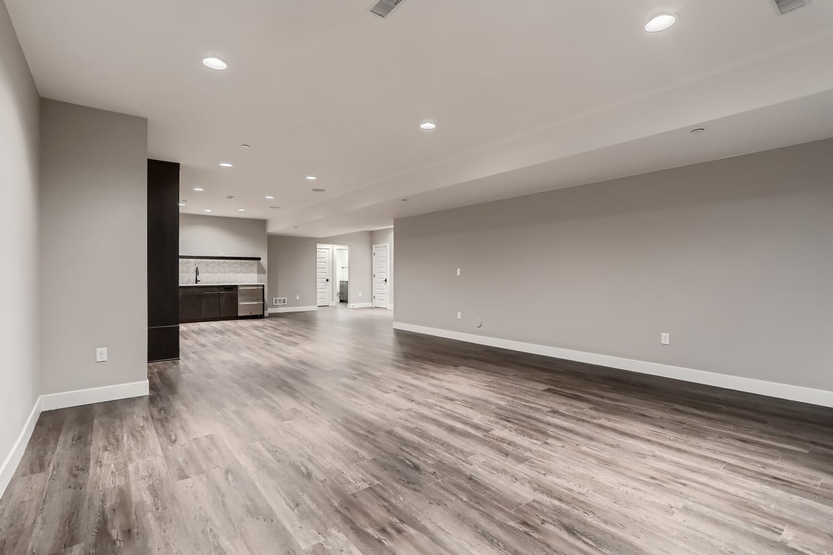 Spacious lower-level family room with vinyl flooring, a wetbar, and recessed lighting by Sheffield Homes in Westminster, CO