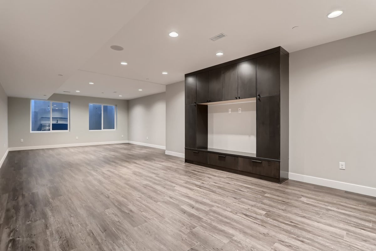 Spacious lower-level family room with vinyl flooring, recessed lighting, and a closet by Sheffield Homes in Westminster, CO