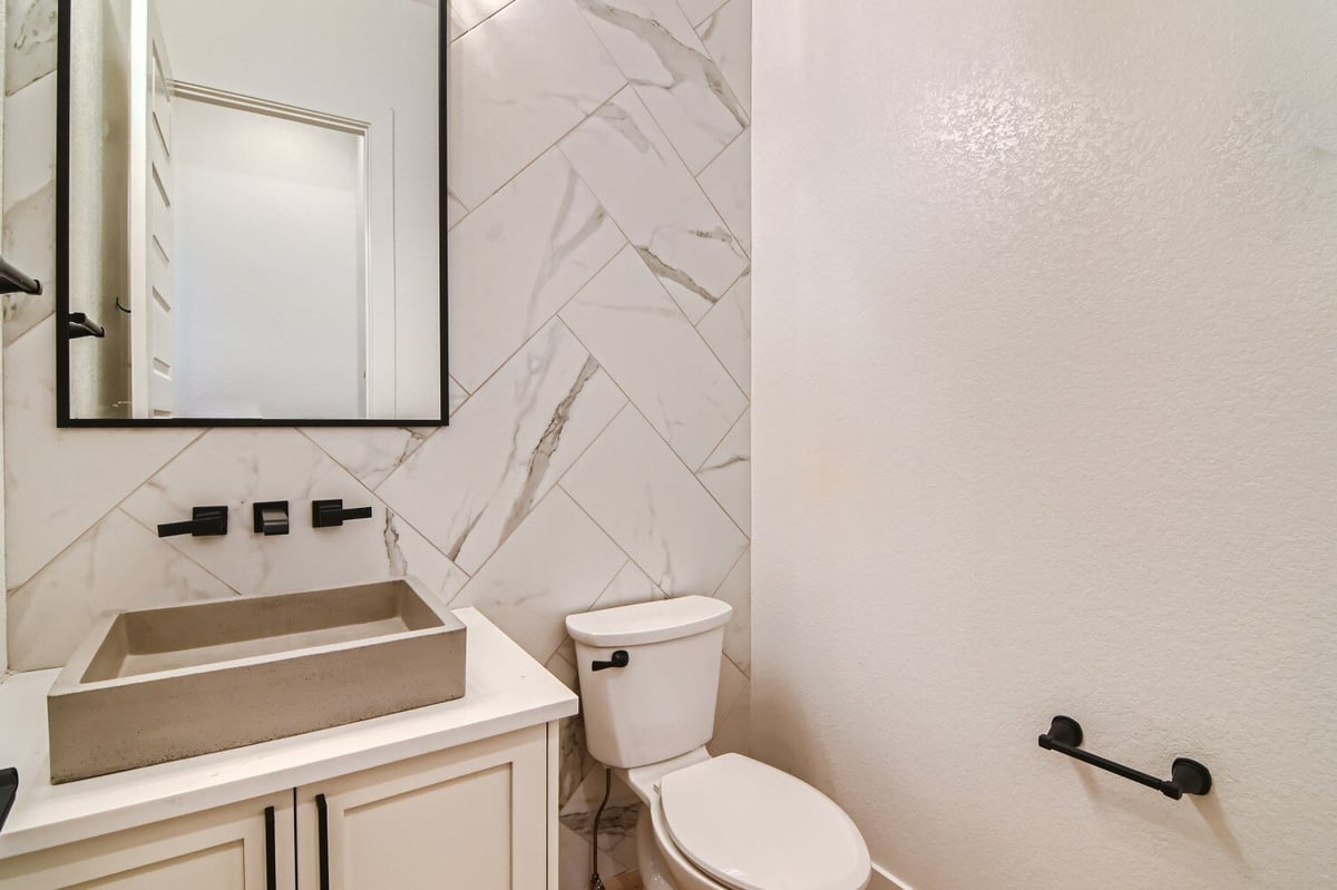 Elegant powder room with a stylish sink faucet and mirror beside a toilet seat in a Sheffield Homes home in Westminster, CO