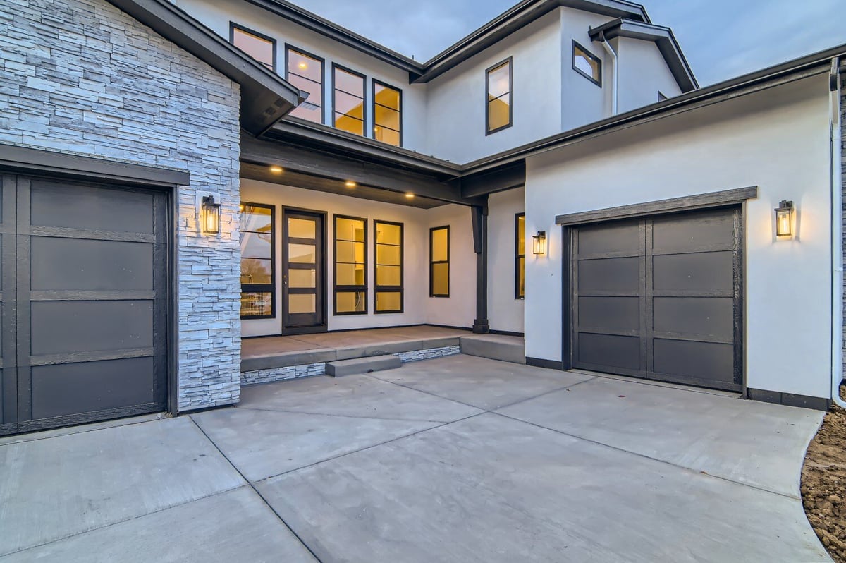 Exterior front entry with a step leading to the door of home featuring stone accent walls by Sheffield Homes, Westminster, CO