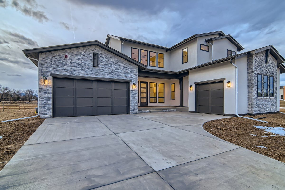 Exterior front of a custom house with a garage and elegant interior lighting in a Sheffield Homes home in Westminster, CO