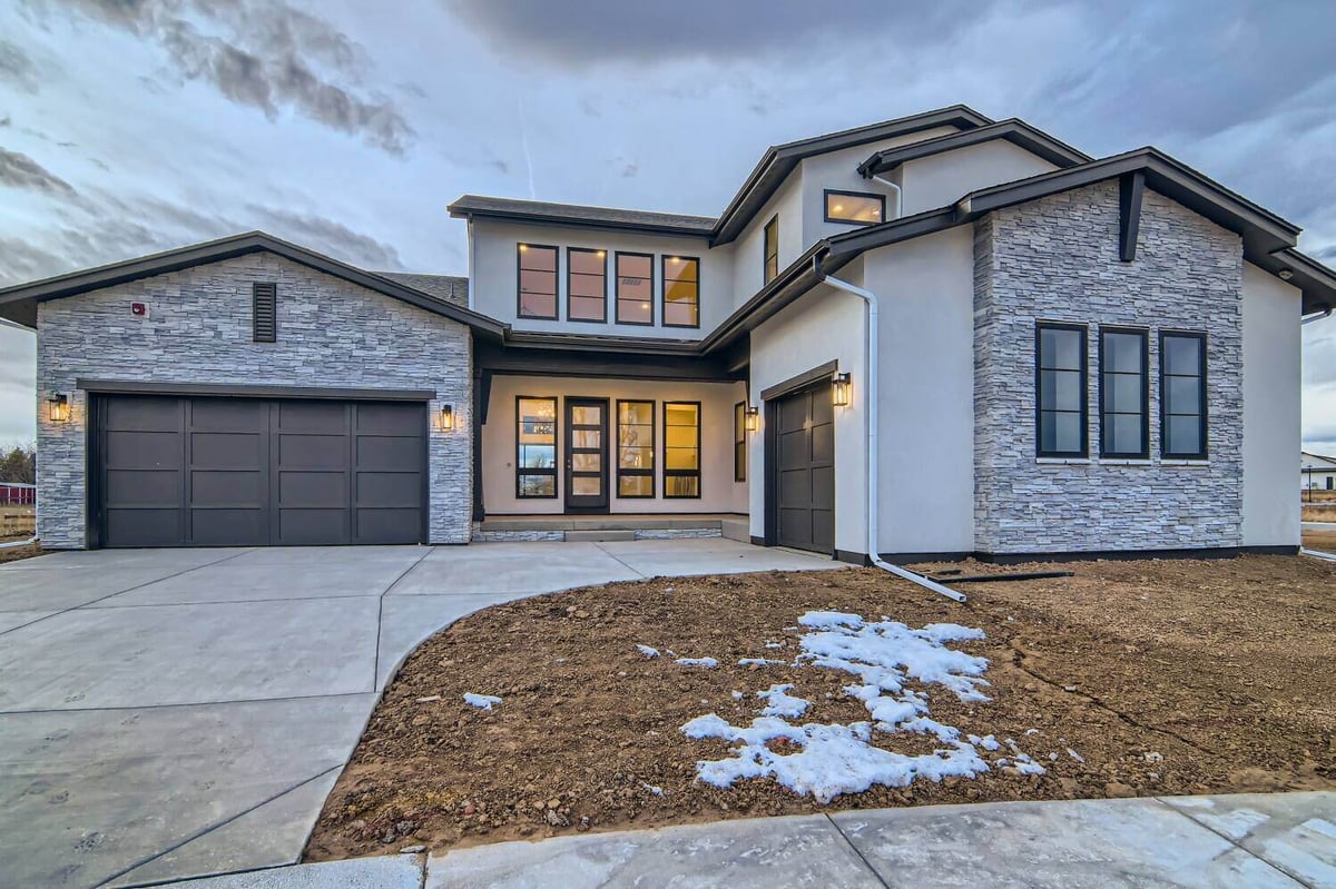 Exterior front of a house with an adjacent garage and stone accent wall design in a Sheffield Homes home in Westminster, CO