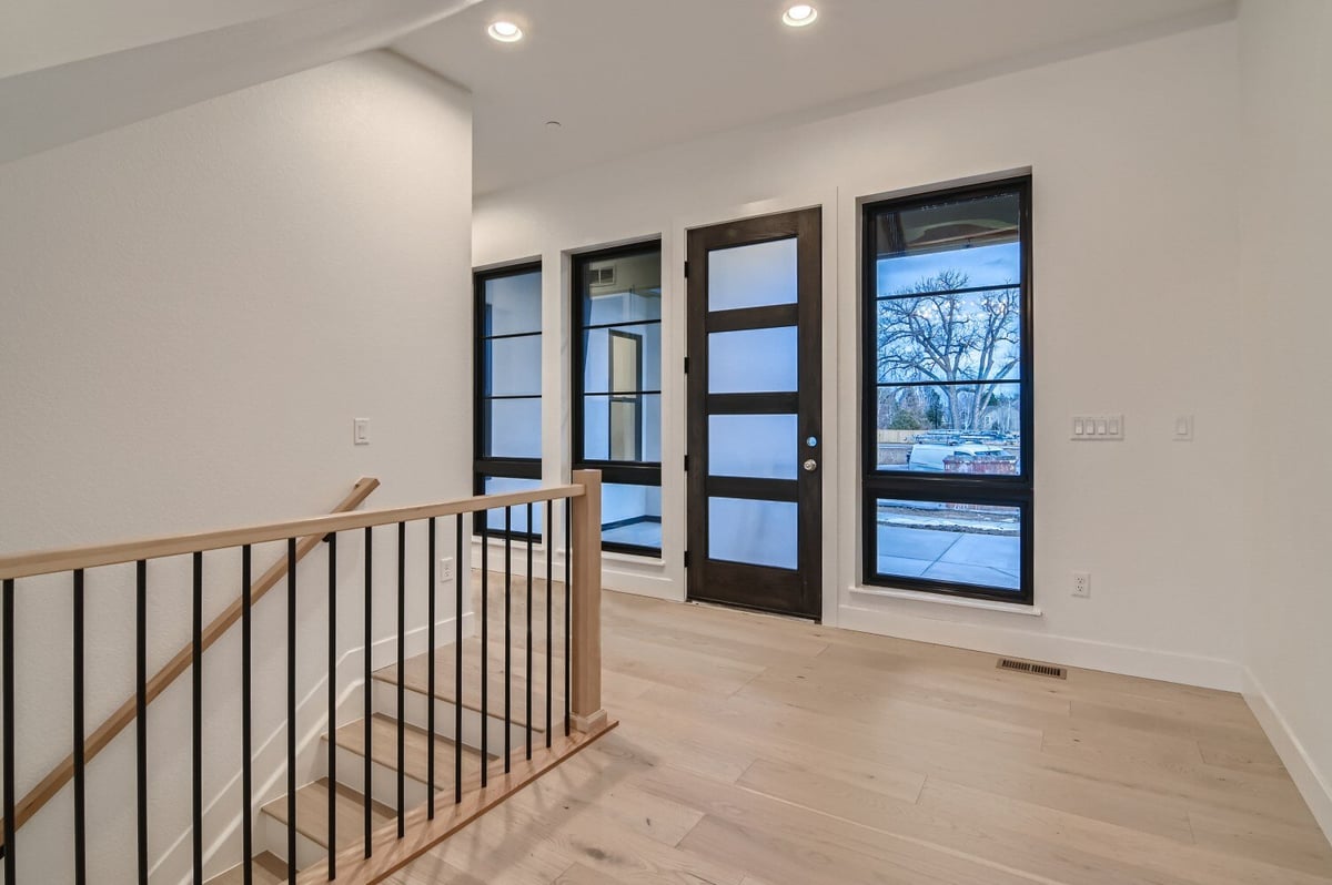 Foyer with a wooden stair railing, metal fencing, and vinyl flooring in a custom home by Sheffield Homes in Westminster, CO