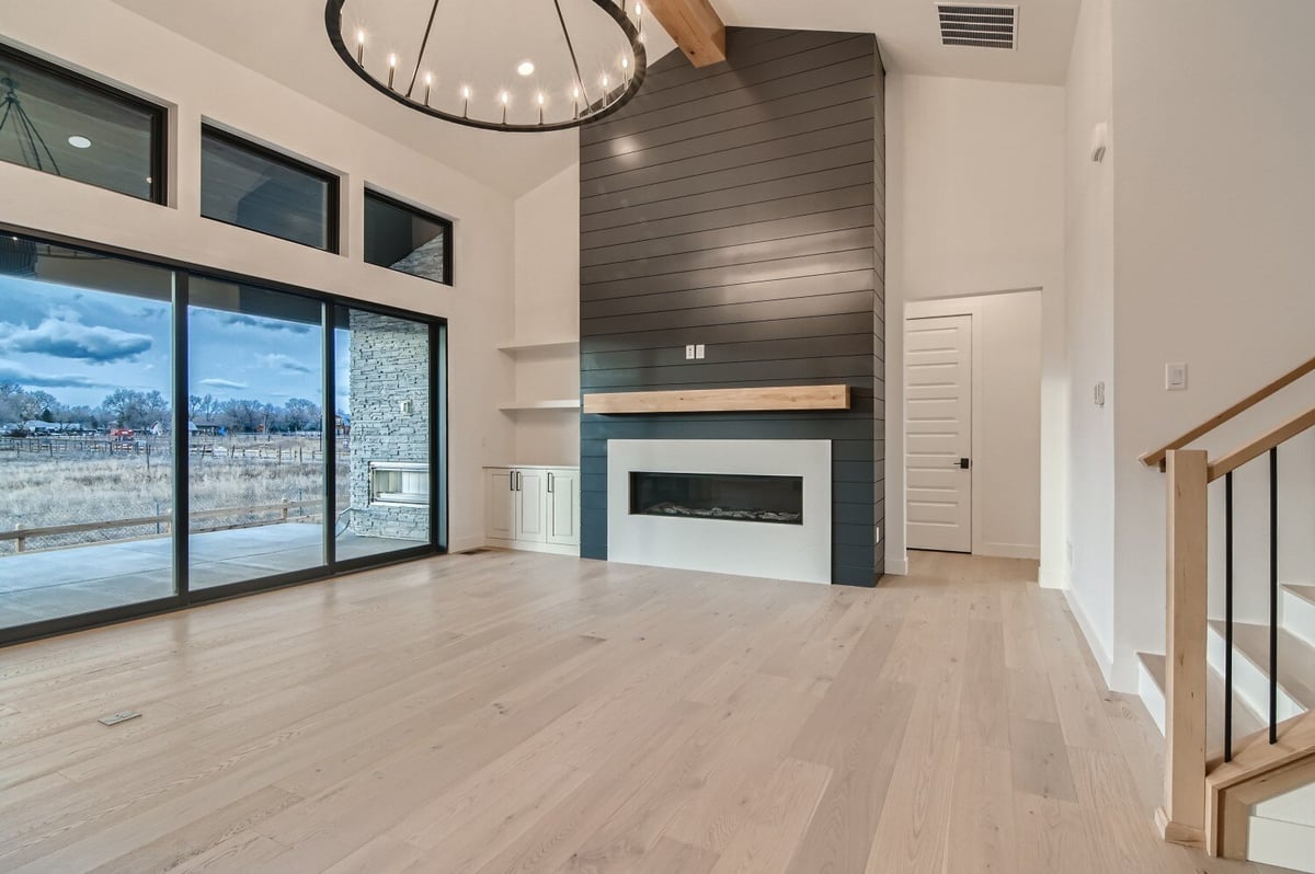 Living room with a corner wall-mounted fireplace and large sliding doors by Sheffield Homes in Westminster, CO