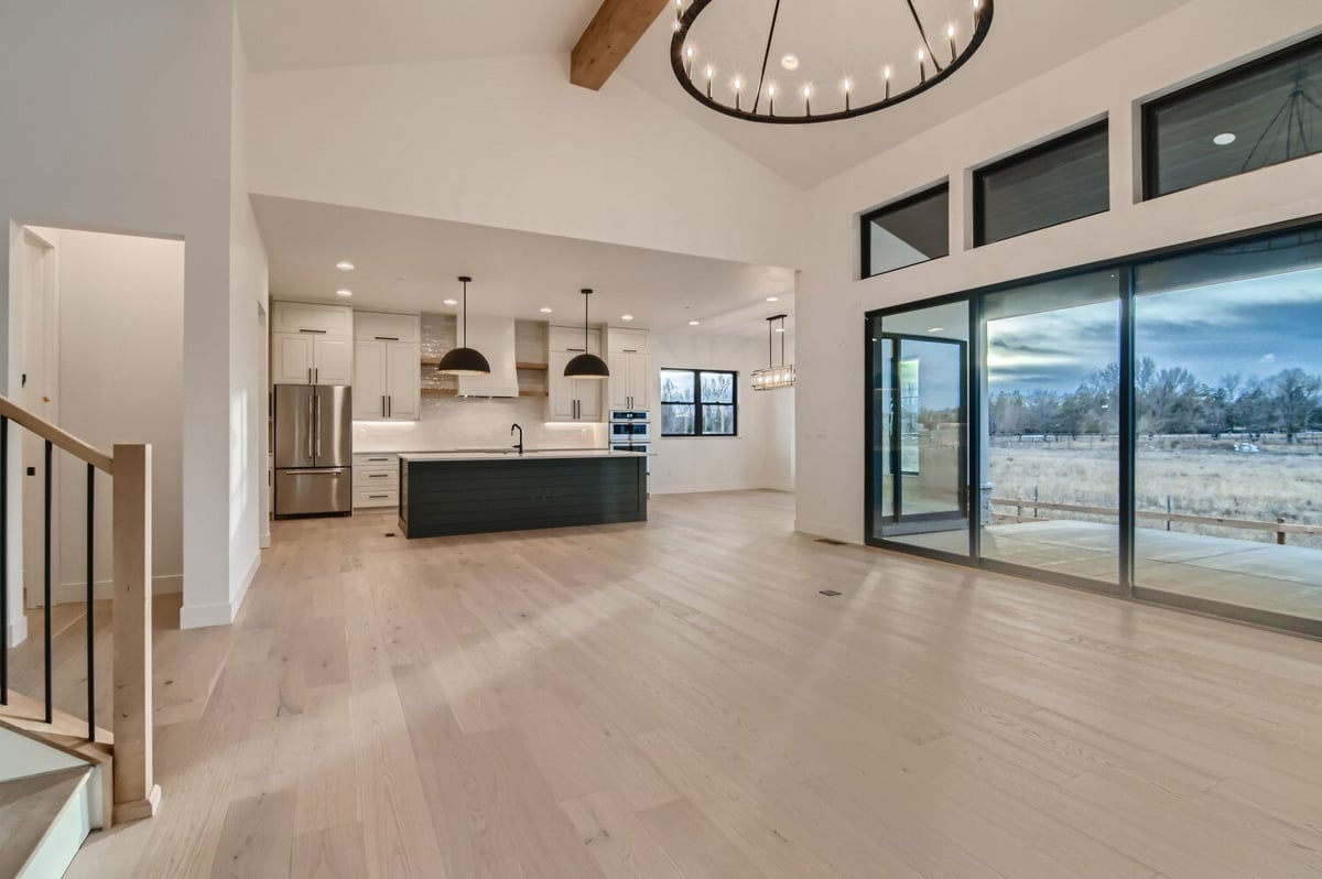 Living room with large sliding doors and a modern open kitchen in a custom home by Sheffield Homes in Westminster, CO