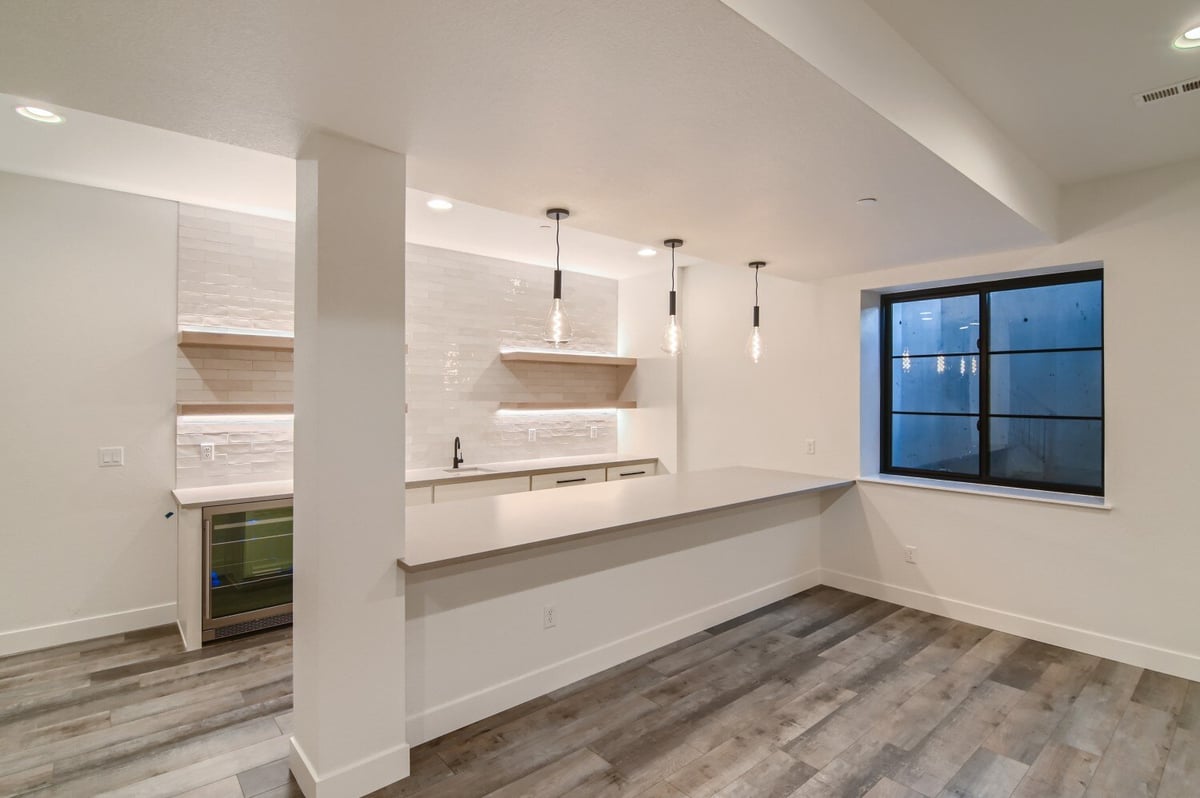 Lower-level kitchen with a seating counter and elegant overhead lighting in a Sheffield Homes home in Westminster, CO