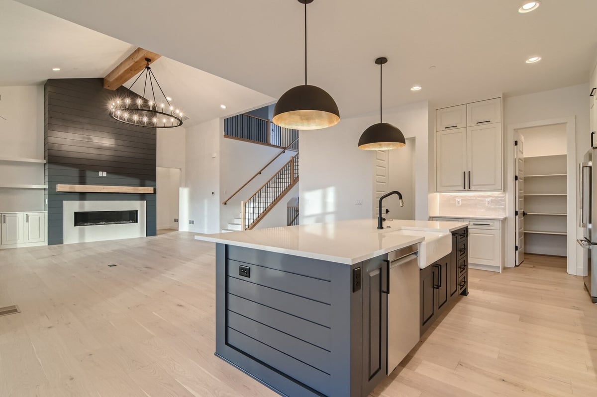 Modern island with dome-shaped pendant lamps overhead in an open kitchen in a Sheffield Homes home in Westminster, CO