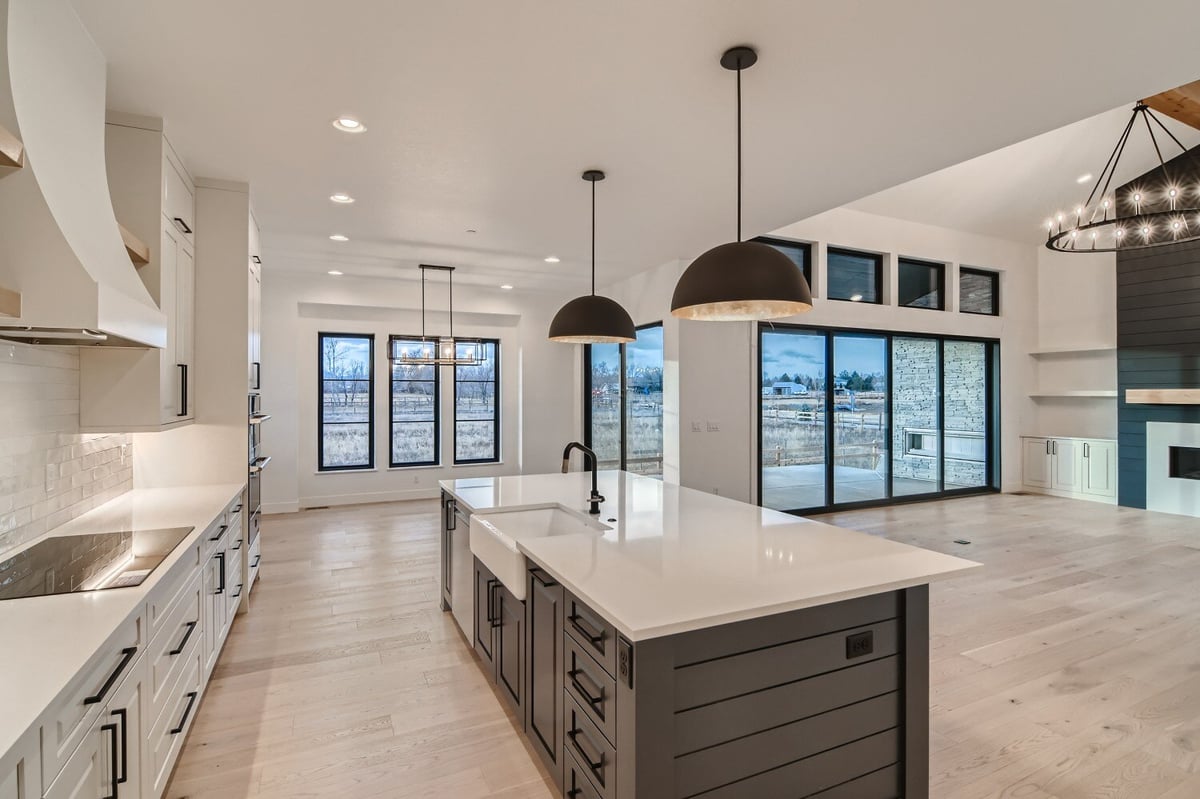 Modern open kitchen with a central island and main counter featuring stove fixtures by Sheffield Homes in Westminster, CO