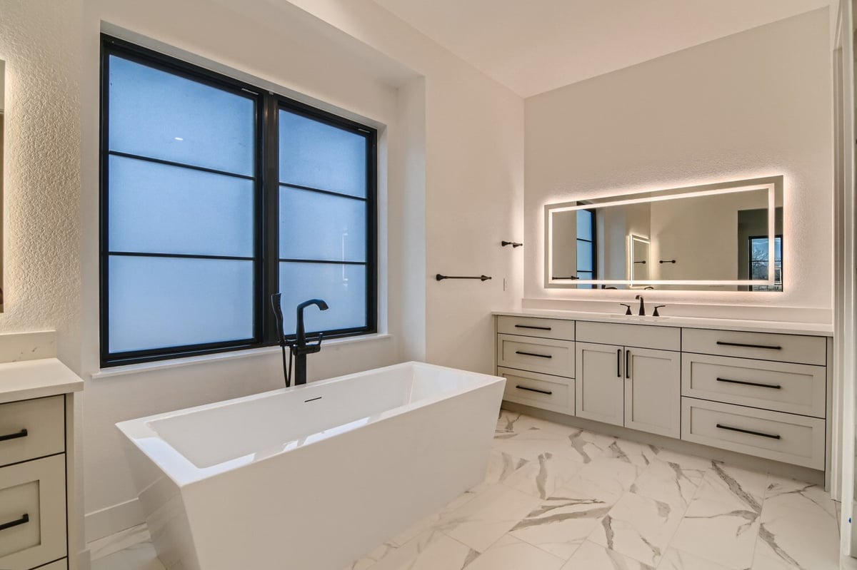 Primary bathroom featuring a bathtub and a vanity with a glowing wall mirror in a Sheffield Homes home in Westminster, CO