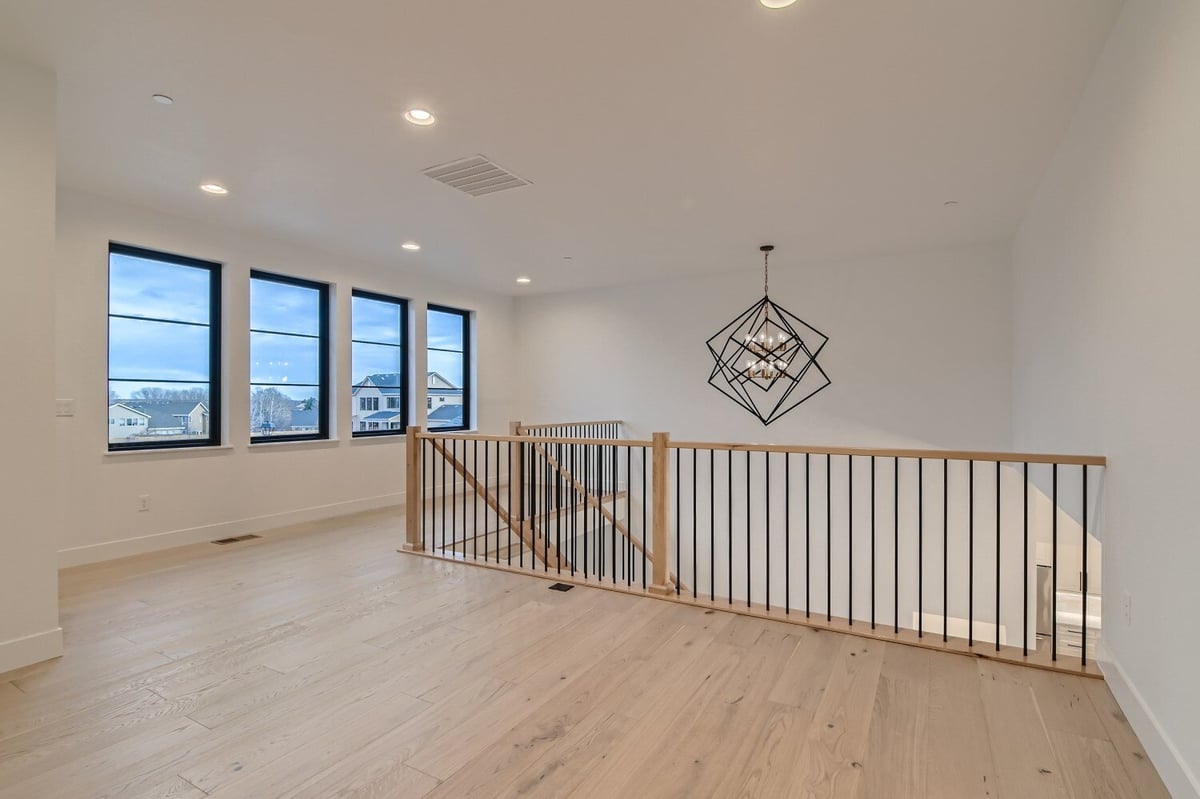 Second-floor loft with a wooden railing and a fancy chandelier for added elegance in a Sheffield Homes home, Westminster, CO