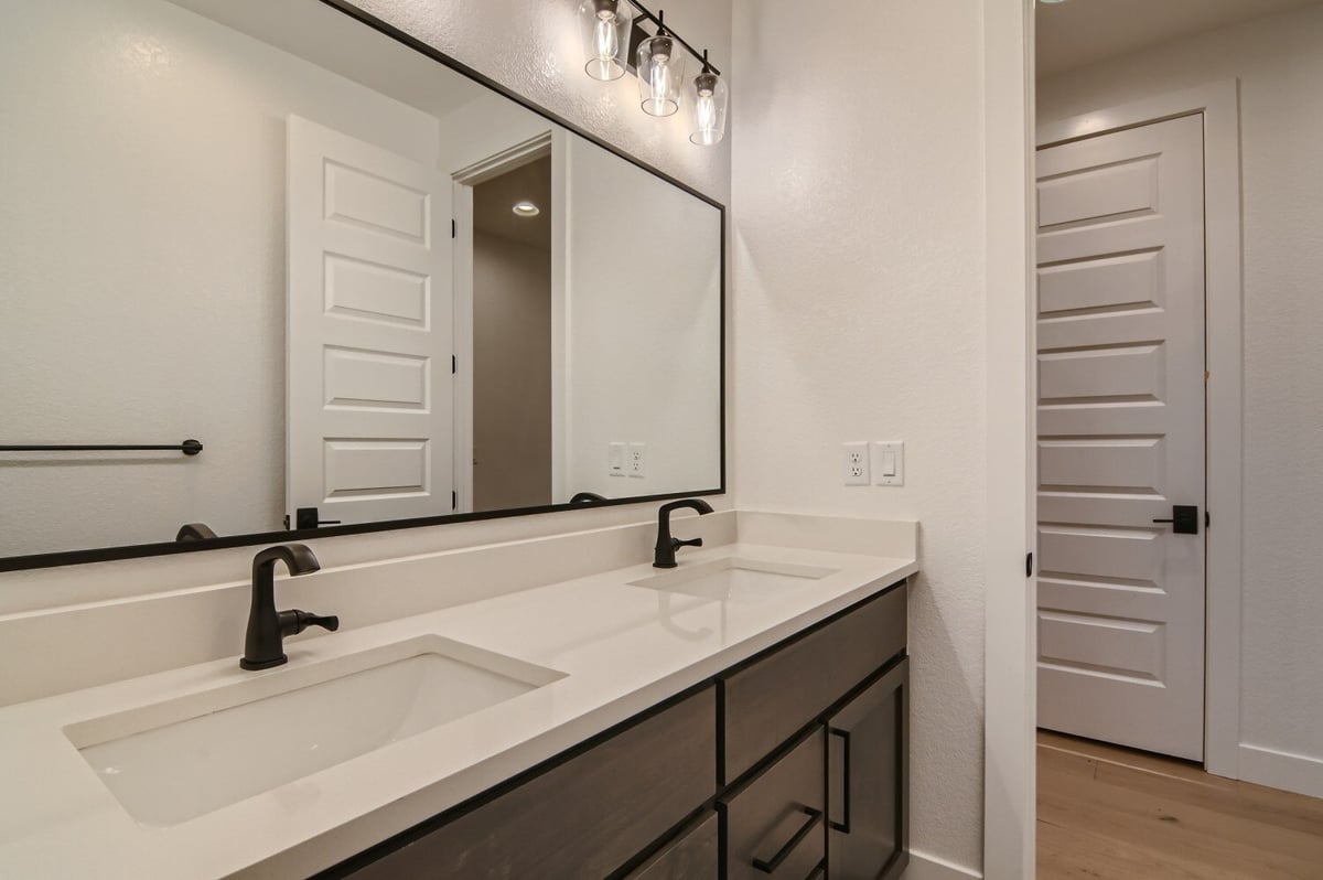 Sleek white and brown bathroom vanity with dual faucets in a custom home by Sheffield Homes in Westminster, CO