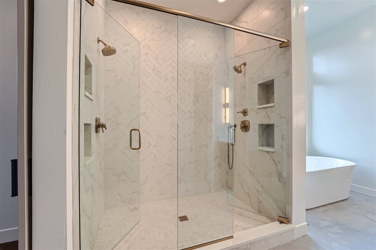 Bathroom with a glass-enclosed shower room featuring golden shower fixtures, by Sheffield Homes in Westminster, CO