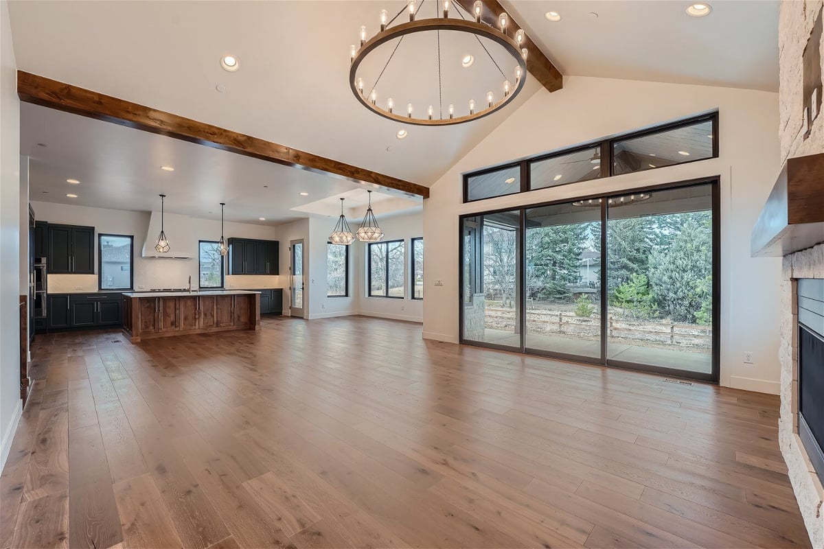 Bright living room with multiple chandeliers for added elegance and an open kitchen by Sheffield Homes in Westminster, CO