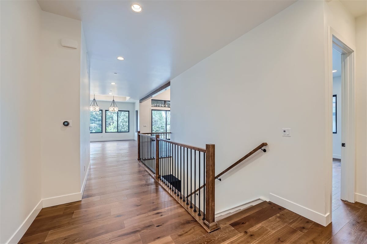 Foyer with dark vinyl flooring, a wooden staircase railing, and metal fencing in a Sheffield Homes home in Westminster, CO