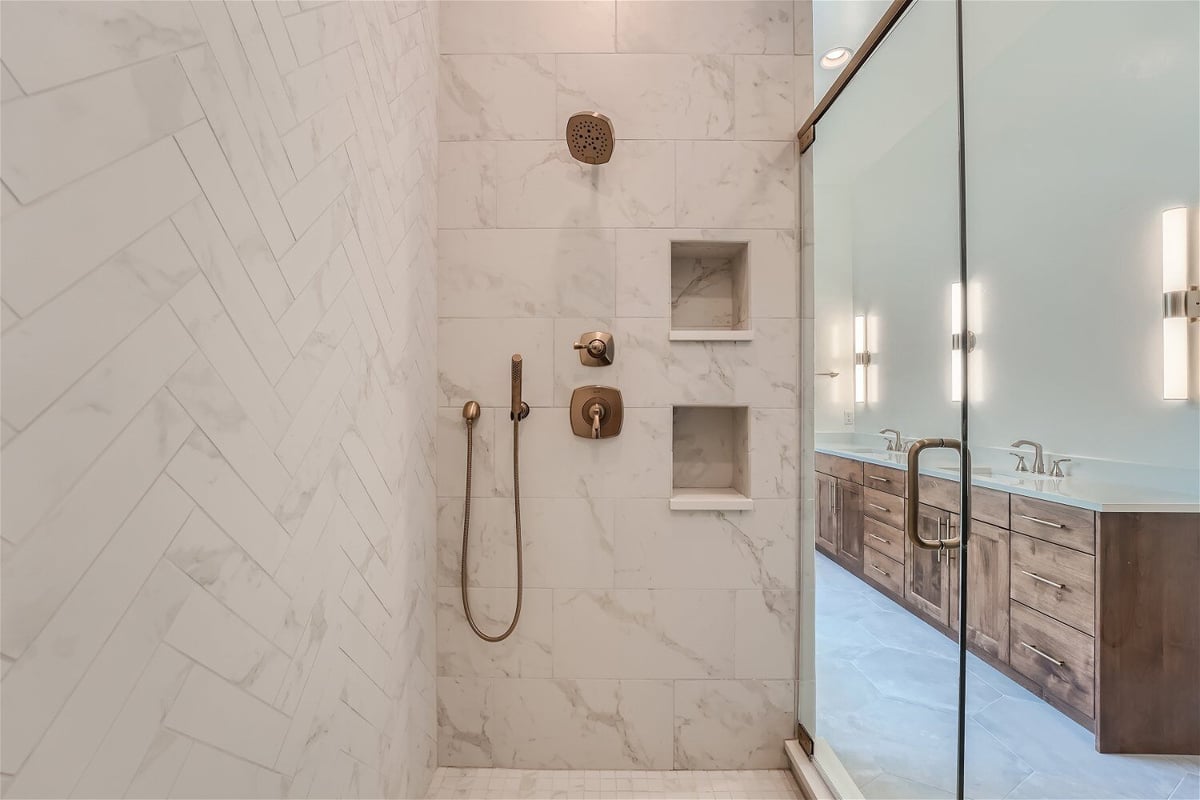 Inside the premium glass-enclosed shower room with golden shower fixtures in a Sheffield Homes home in Westminster, CO