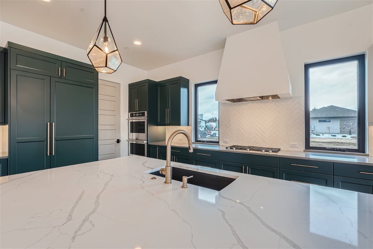 Kitchen island with a central island, faucet, and an extractor hood on the rear wall, by Sheffield Homes in Westminster, CO