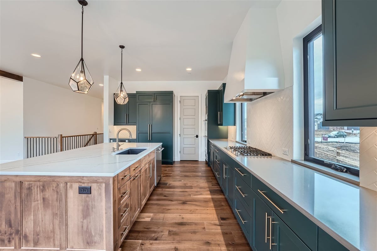 Kitchen with an island, rear counter, vinyl flooring, and elegant light fixtures by Sheffield Homes in Westminster, CO