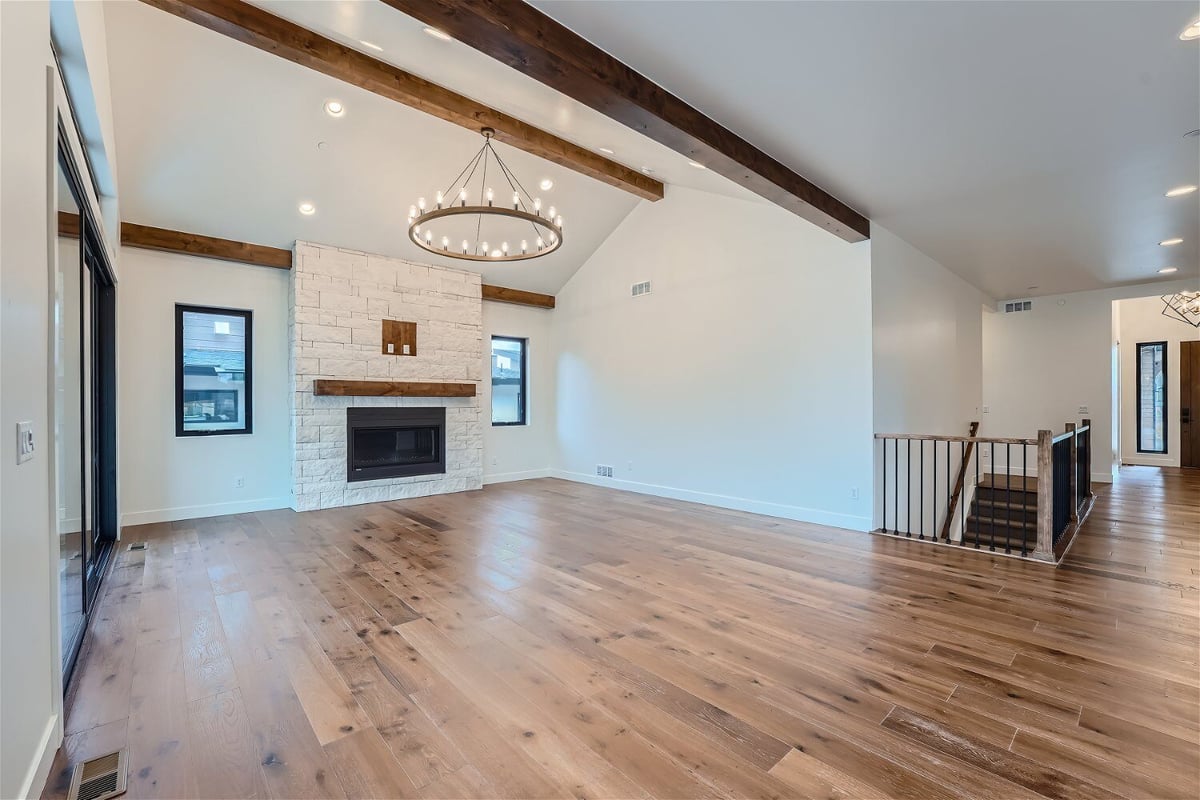 Living room with vinyl flooring, a centred chandelier, and a wall-mounted fireplace by Sheffield Homes in Westminster, CO