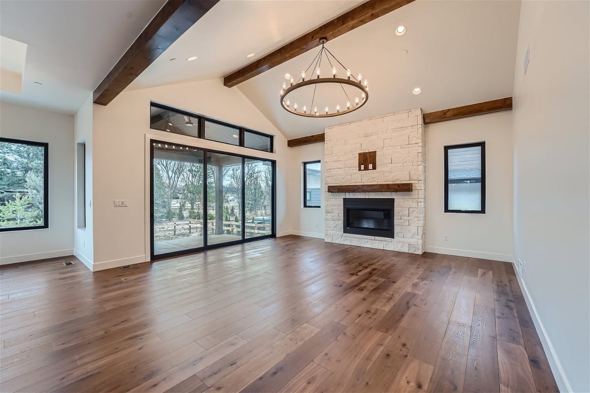 Living room with vinyl flooring, a chandelier, a fireplace, and large sliding doors by Sheffield Homes in Westminster, CO