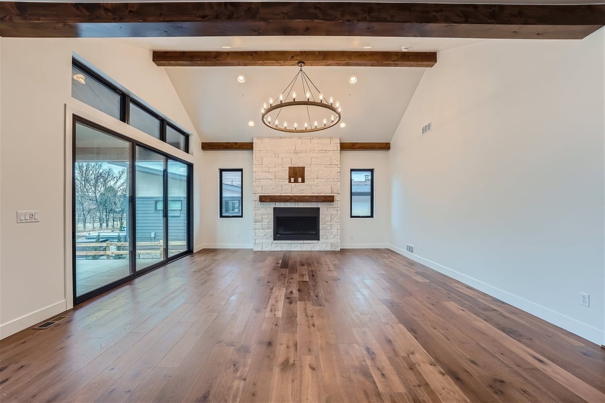 Living room with vinyl flooring, a chandelier, and large sliding main doors in a Sheffield Homes home in Westminster, CO