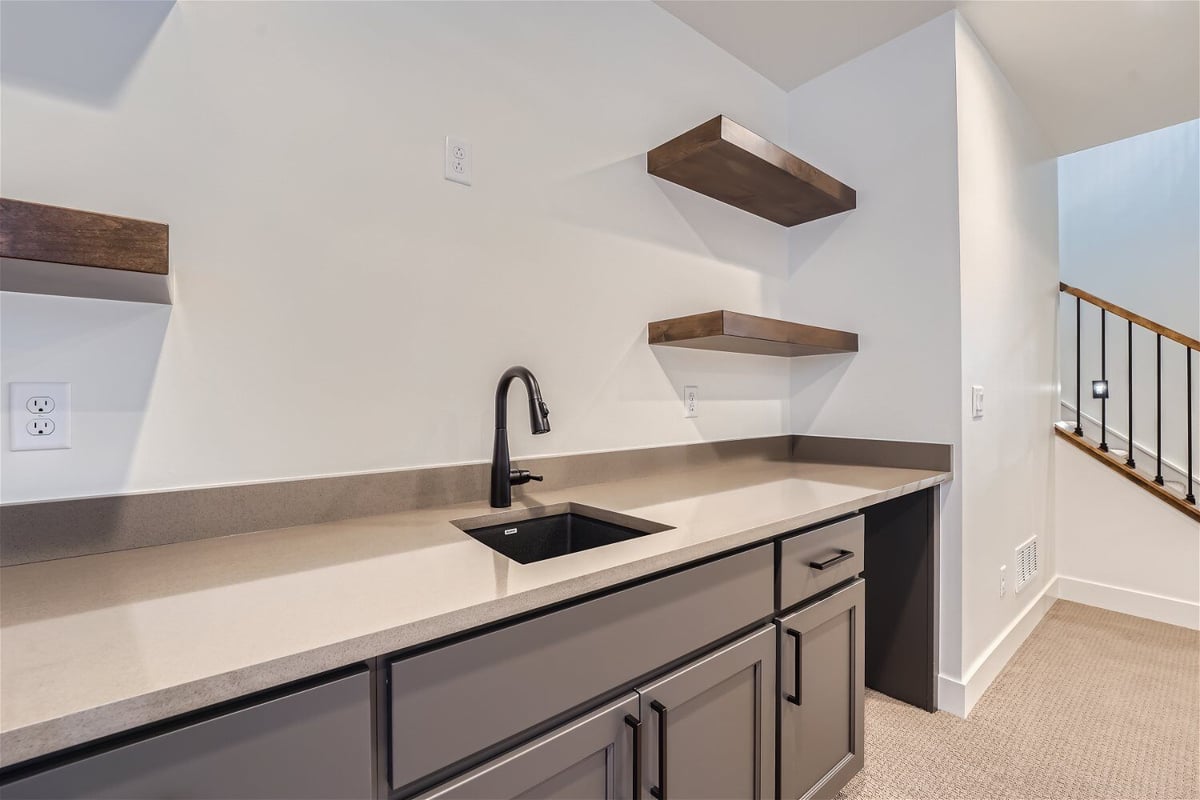 Lower-level wet bar with a sink faucet, and wooden wall shelves for storage, by Sheffield Homes in Westminster, CO