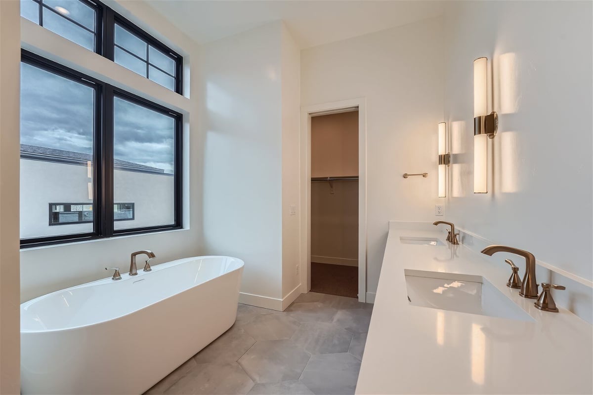 Primary bathroom with a freestanding tub and a white top basin with dual faucets by Sheffield Homes in Westminster, CO