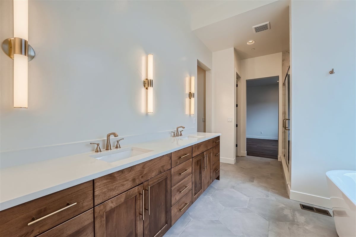 Primary bathroom with marble flooring, multiple basin faucets, and cabinetry base by Sheffield Homes in Westminster, CO