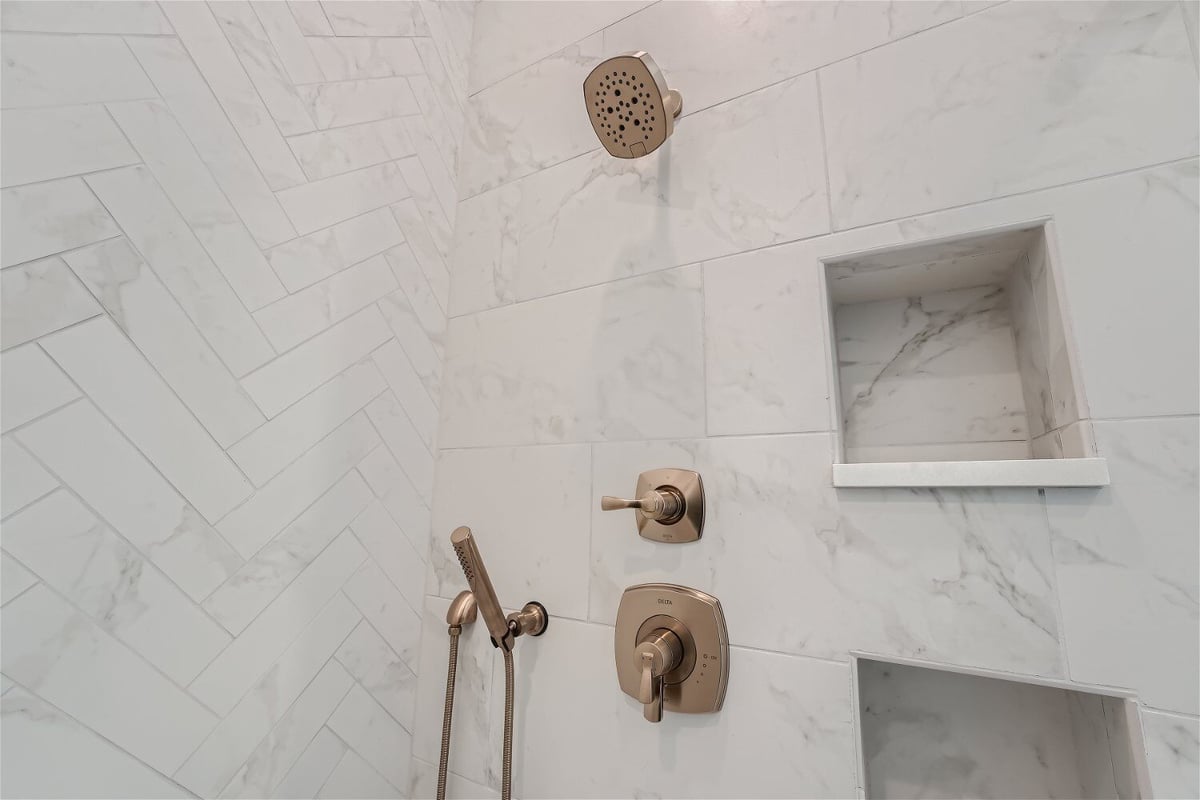 Primary bathroom_s shower area with golden shower fixtures on a tiled wall in a Sheffield Homes home in Westminster, CO