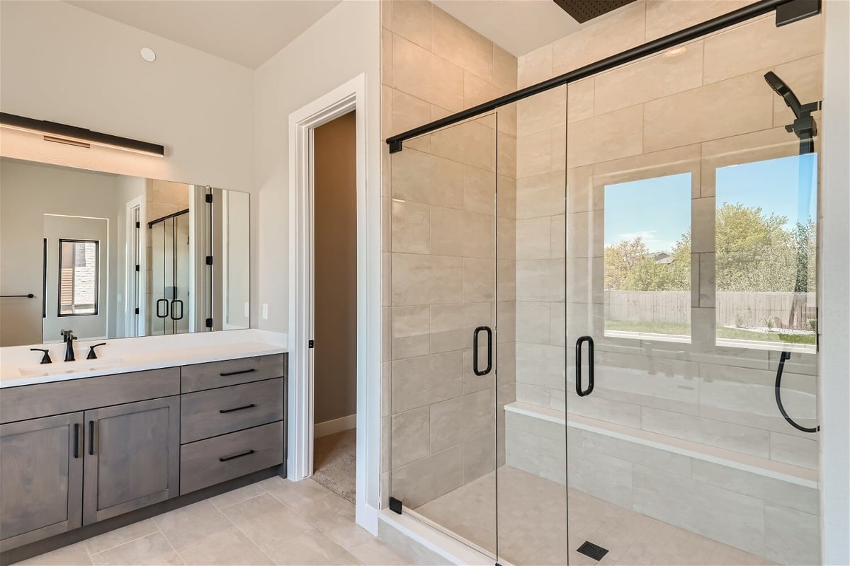 Bathroom with a modern shower enclosure and a stylish vanity with cabinets, by Sheffield Homes in Westminster, CO