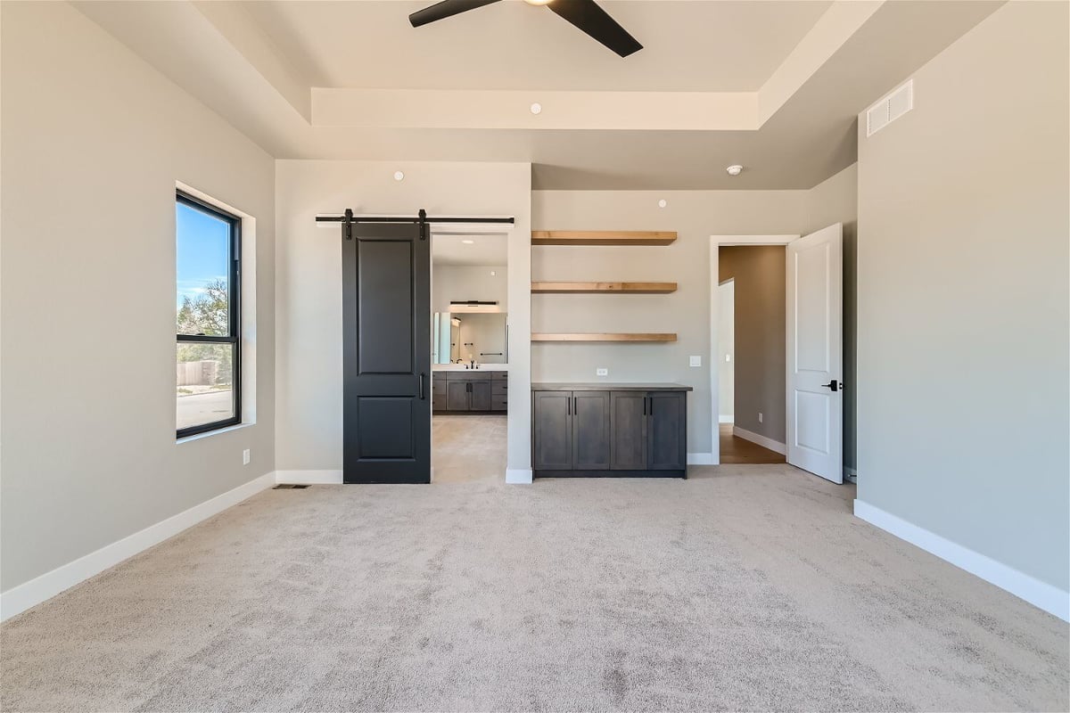 Bedroom with carpet flooring, a sliding bathroom door, and a side dresser, by Sheffield Homes in Westminster, CO