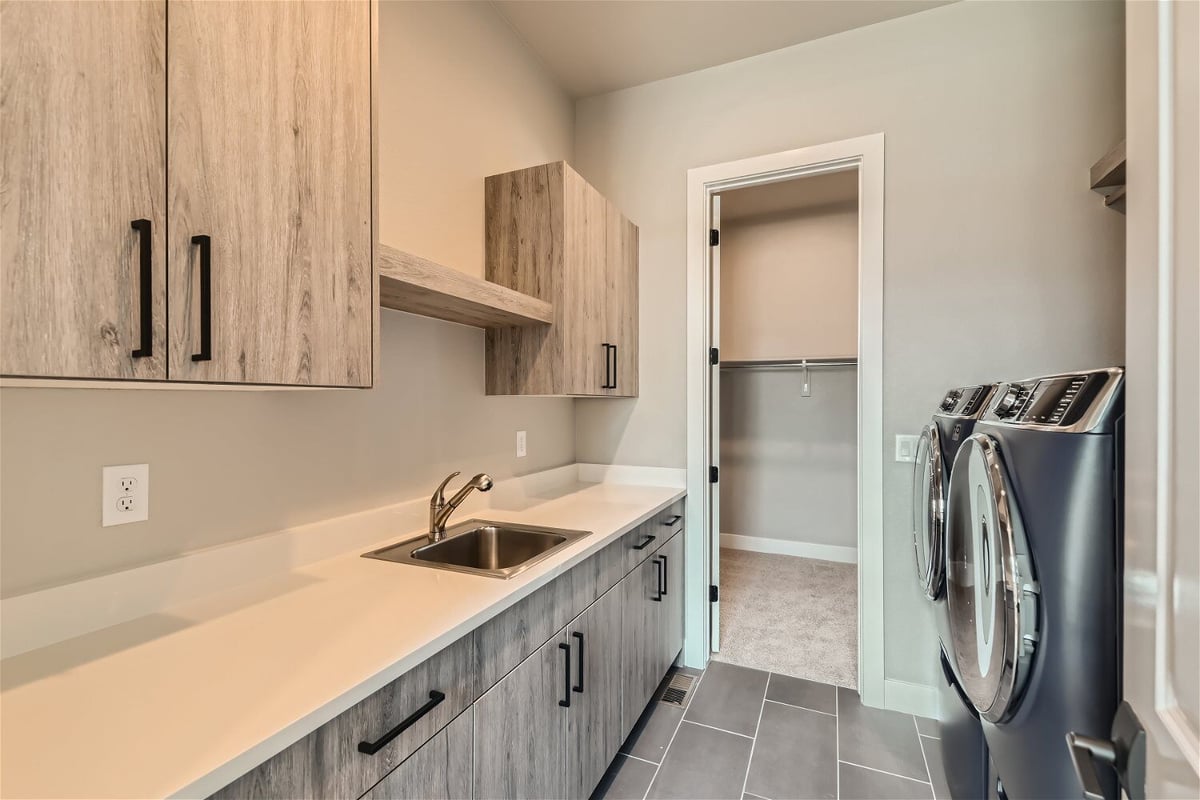 Laundry room with natural wooden cabinetry, a sink, and washing machines, by Sheffield Homes in Westminster, CO