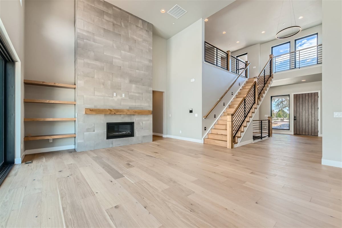 Living room with wood-texture flooring, a staircase, and a corner fireplace in a Sheffield Homes home in Westminster, CO