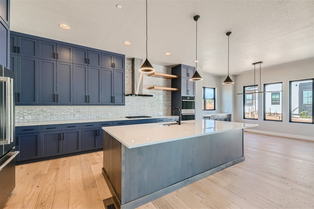 Modern open kitchen with a central island, rear cabinetry, and elegant light fixtures by Sheffield Homes in Westminster, CO