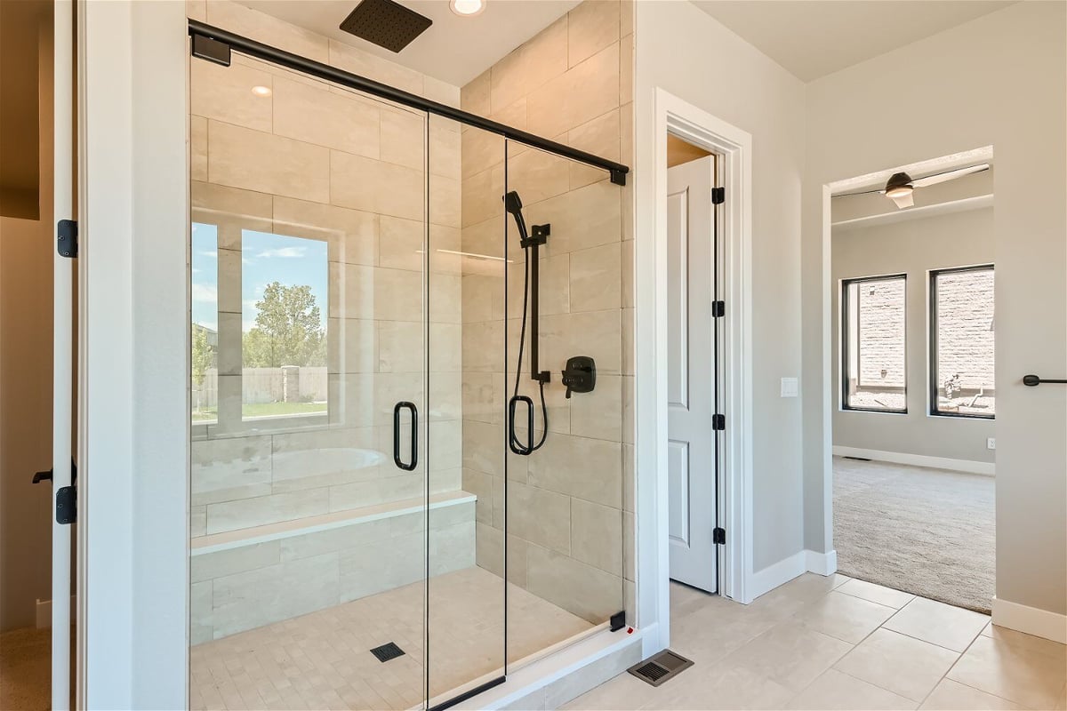 Premium shower enclosure with black shower fixtures and glass doors, by Sheffield Homes in Westminster, CO