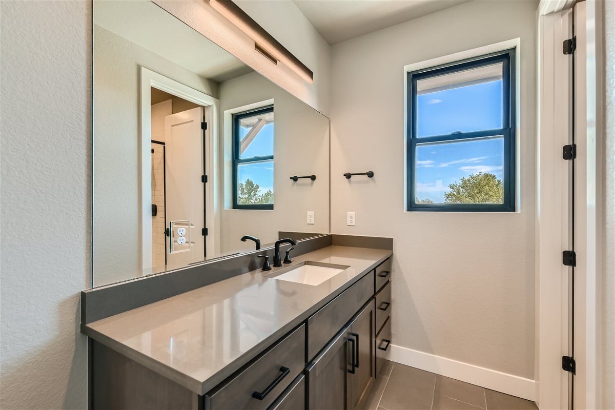 Second-floor bathroom with a sleek modern vanity, a large mirror, and a single faucet, by Sheffield Homes in Westminster, CO