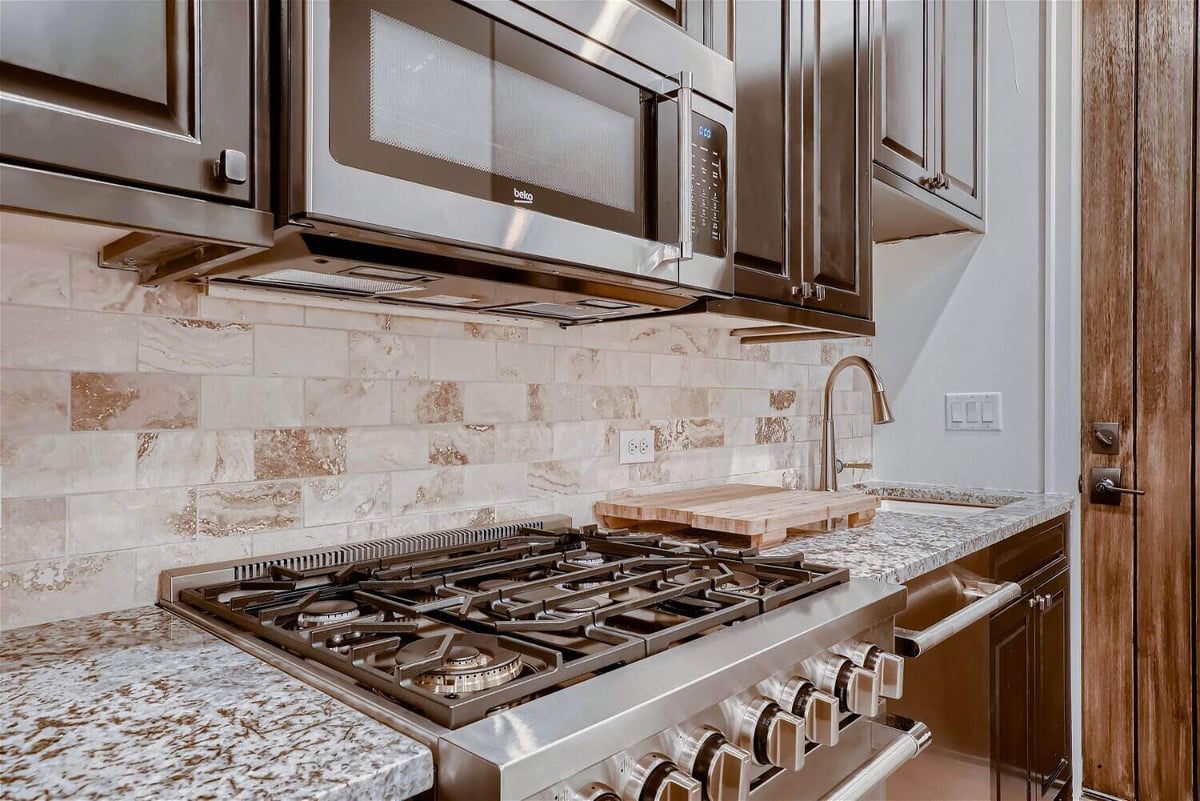 Close-up of stove fixtures and a mounted microwave in a custom home kitchen by Sheffield Homes in Westminster, CO