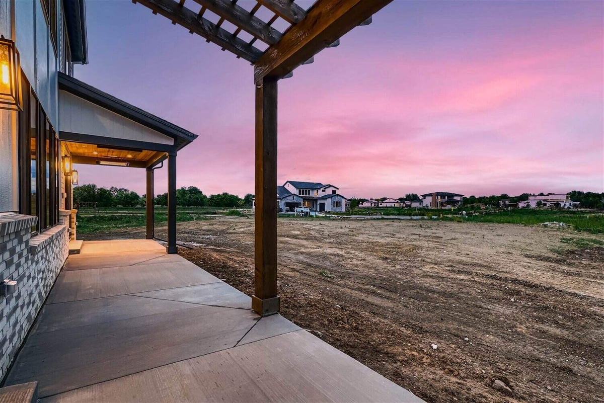 Custom outdoor patio with a wooden hood and pillars overlooking the backyard, by Sheffield Homes in Westminster, CO