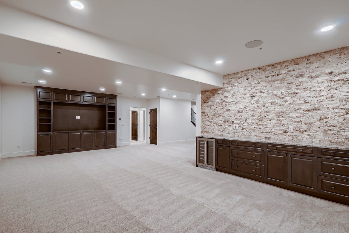 Family room with carpet flooring, a stone accent wall, and wooden closets in a Sheffield Homes home in Westminster, CO