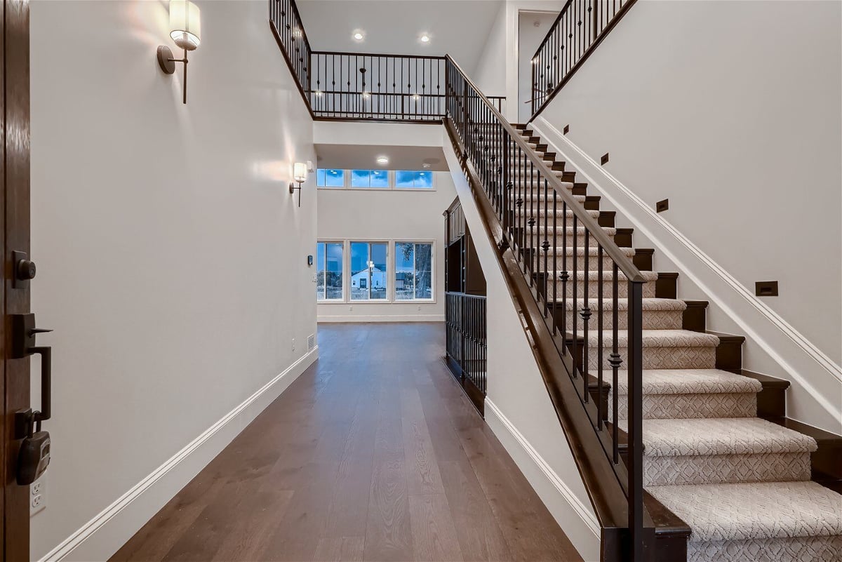 Foyer with vinyl flooring, mini wall-mounted lamps, and a stylish staircase in a Sheffield Homes home in Westminster, CO