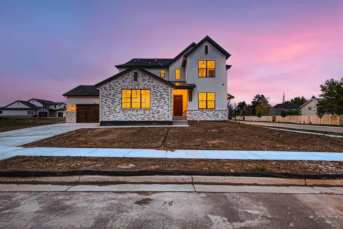 Long shot exterior front view of a custom home with elegant lighting inside, by Sheffield Homes in Westminster, CO